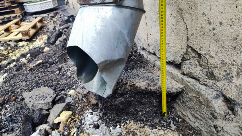 Замер расстояния у выпуска водосточной трубы на фасаде здания