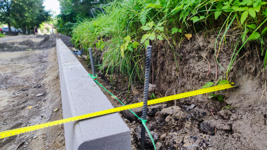 Линия бордюра с разметочным шнуром и металлическими штырями на этапе устройства основания дороги