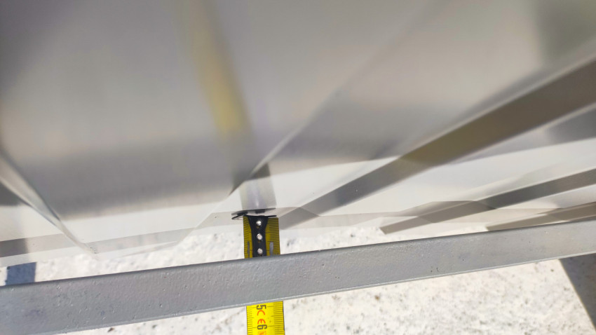 Измерение зазора на ограждении контейнерной площадки строительной рулеткой с металлическим крюком