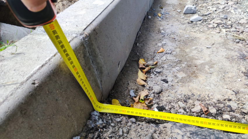 Вертикальный замер высоты бордюрного камня рулеткой на щебёночном основании