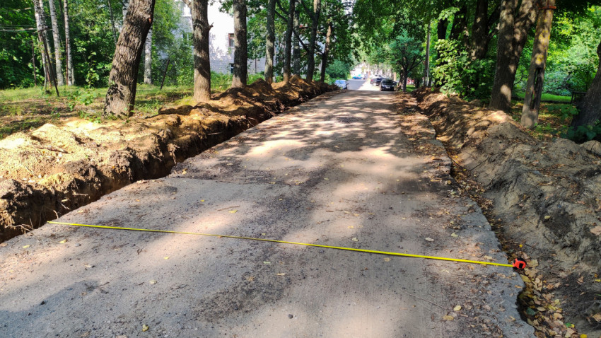 Контрольный замер рулеткой рядом с траншеей при земляных работах