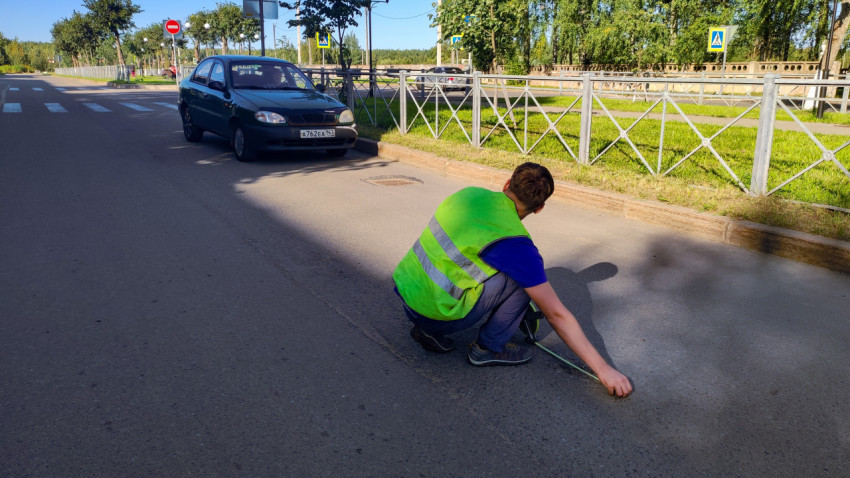Дорожный замер у перекрёстка: рулетка, выбоина и рабочий в жилете