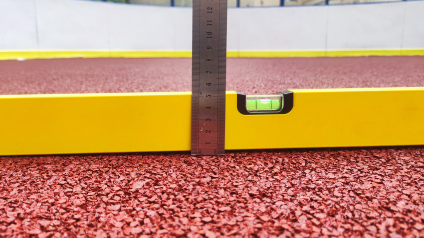 Строительный уровень и линейка на покрытии из резиновой крошки