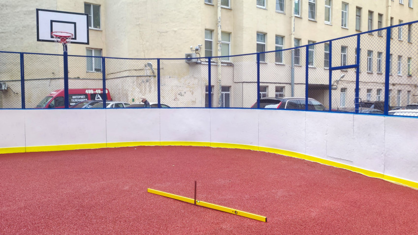 Жёлтый строительный уровень на резиновом покрытии дворовой спортивной площадки