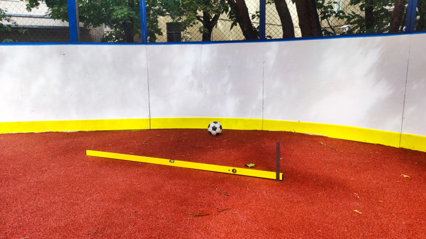 Футбольный мяч и строительный уровень на дворовой спортплощадке