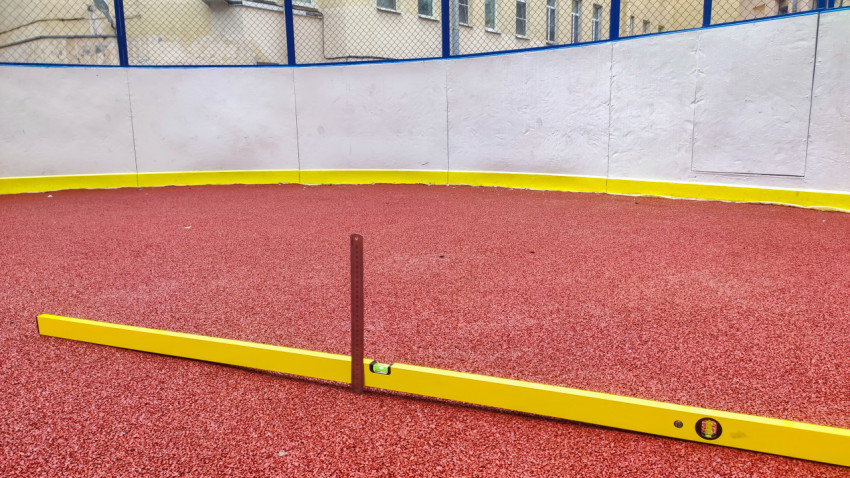 Проверка ровности резинового покрытия уровнем и металлической линейкой у бортов спорткоробки