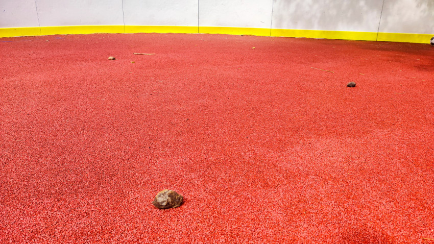 Камни и мусор на красном резиновом покрытии площадки