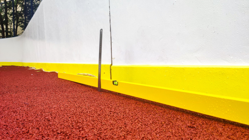 Строительный уровень и линейка у борта спортивной площадки