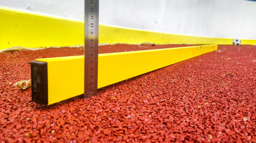 Металлическая линейка и желтая рейка для замера перепадов высоты покрытия