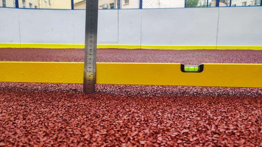 Линейка и пузырьковый уровень на резиновом покрытии спортплощадки