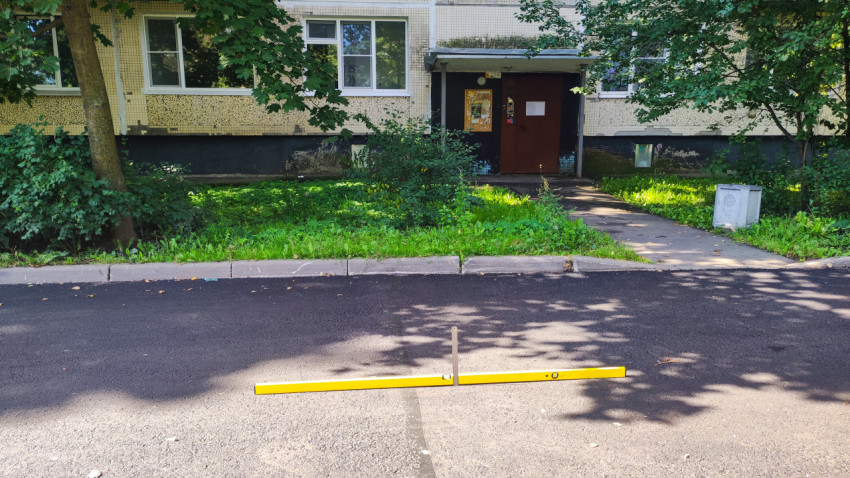 Проверка перепада по кромке асфальта уровнем и линейкой у входа в подъезд