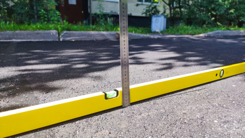 Контроль ровности покрытия строительным уровнем и линейкой на свежем асфальте