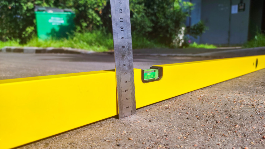 Крупный план измерительной рейки на уровне при проверке уклона асфальтового покрытия