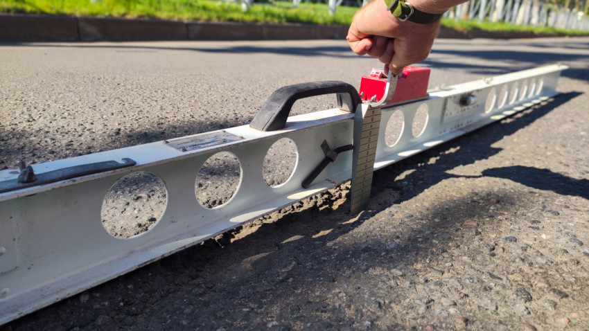 Неровность покрытия проверяют рейкой с уровнем и клин-промерником прямо на асфальте