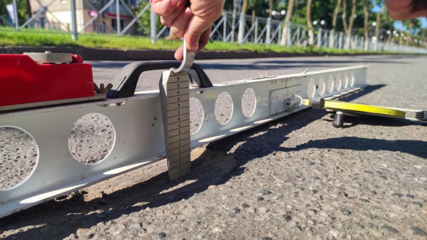 Крупный план: клин и рейка-правило для проверки неровностей асфальта