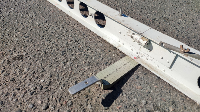 Замер просвета под контрольной рейкой на дороге с помощью клинового щупа и фиксирующего узла