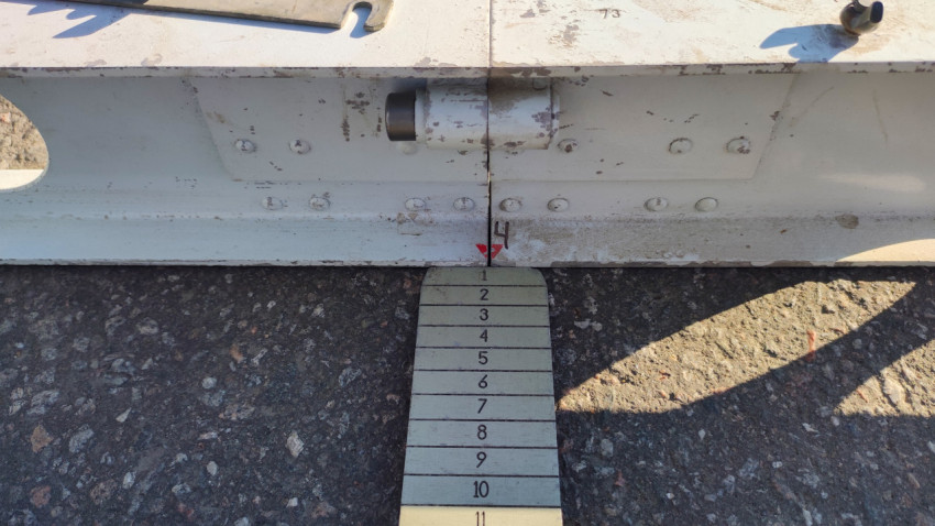 Клин-промерник под рейкой показывает неровность покрытия на дорожном участке