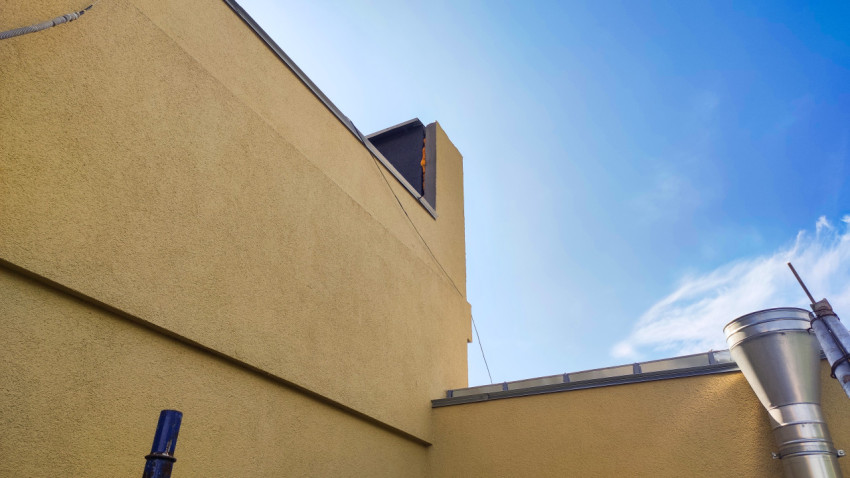 Технический дворик между стенами с вентиляционной трубой и воздуховодом