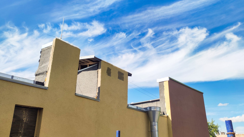 Парапеты плоской крыши с вентиляционной решёткой и металлическим воздуховодом