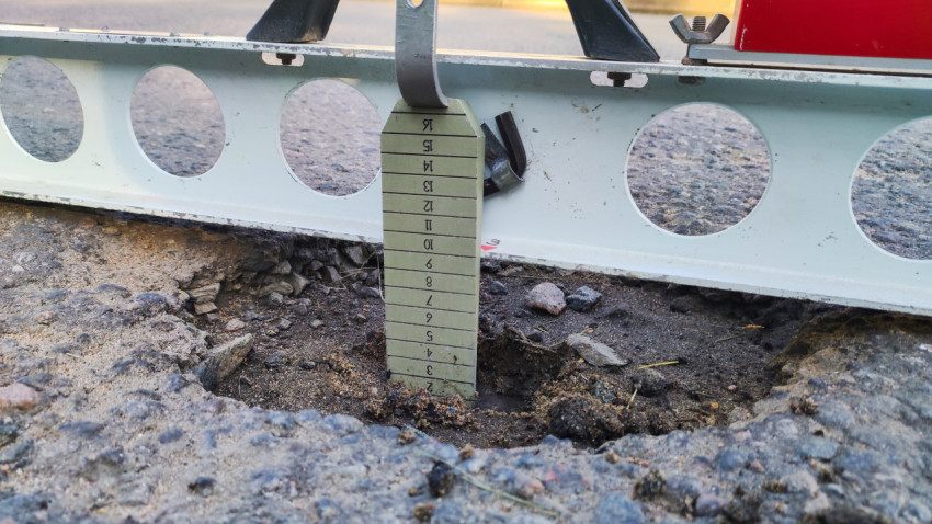 Клин с разметкой стоит в яме под рейкой, видно насколько просел асфальт