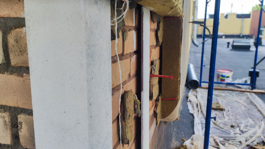 Ремонт оконного проема с открытой кирпичной кладкой и монтажными слоями на настиле лесов