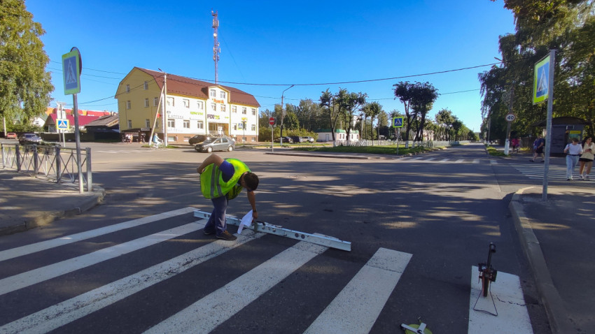 Дорожник проверяет разметку «зебра» металлической рейкой прямо на перекрёстке