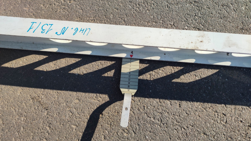 Крупно: клин-промерник под рейкой снимает значение ровности дорожного покрытия