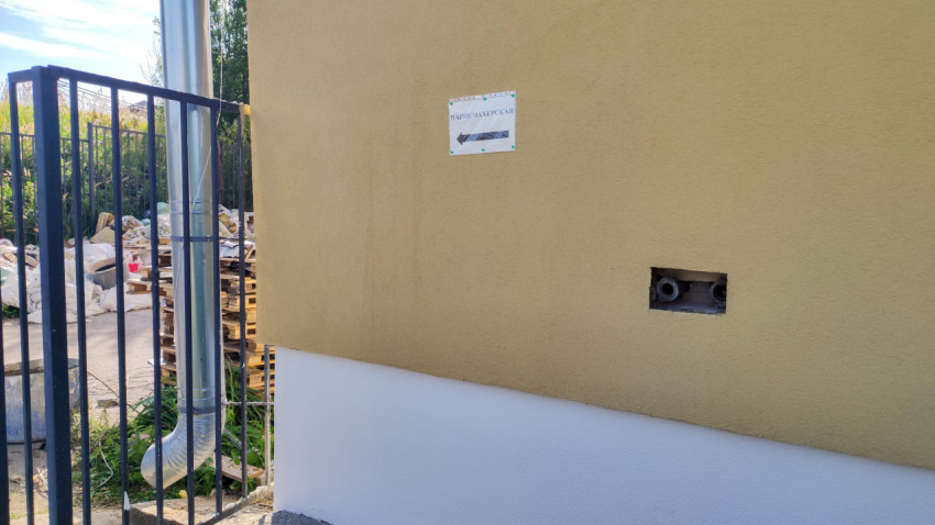 Навигационная табличка «ПАРИКМАХЕРСКАЯ» на фасаде рядом с водосточной трубой и технологическим отверстием с трубами