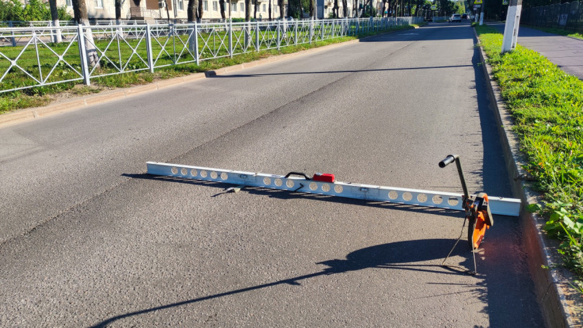 Рейка и мерное колесо на дороге, пока проверяют ровность покрытия
