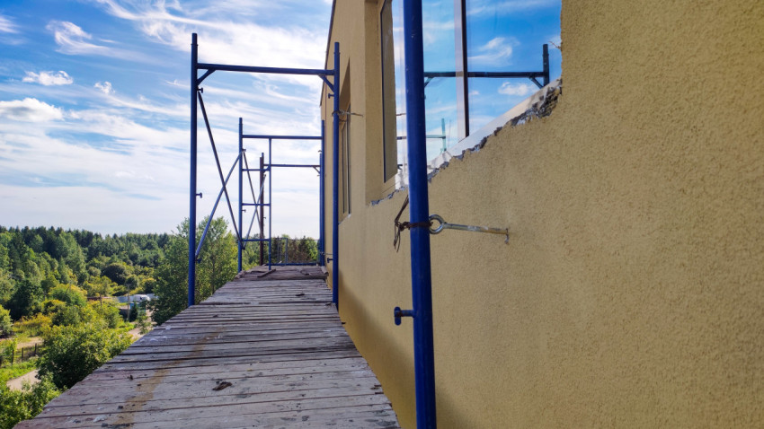 Деревянный настил строительных лесов у фасада на фоне лесного пейзажа