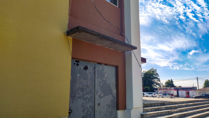 Служебный вход в здание с металлическими дверями, бетонным козырьком и лестницей из тротуарной плитки