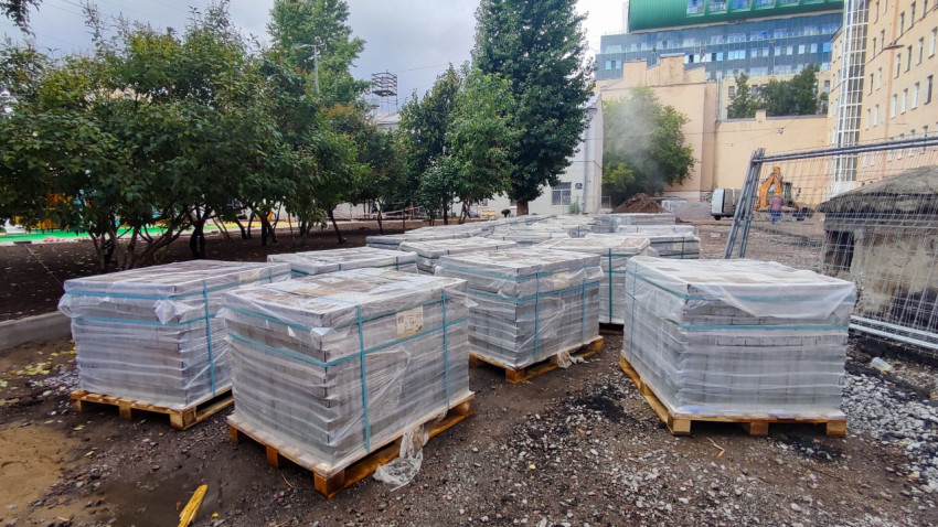 Паллеты с тротуарной плиткой на площадке благоустройства во дворе