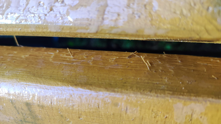 Текстура мокрой лакированной древесины с царапинами и занозами на рейках скамейки