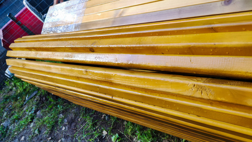 Боковая сторона новых скамеек с мокрыми деревянными рейками и защитной плёнкой