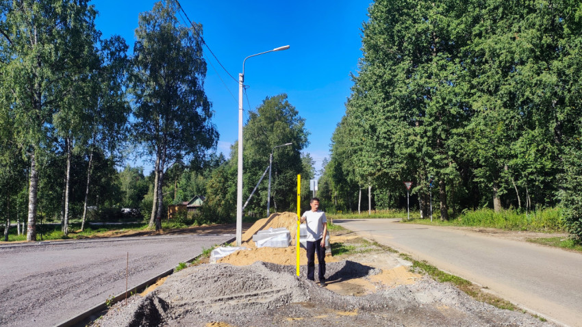 Рабочий на ремонтируемой площадке измеряет высоту слоя песка мерной рейкой у проезда