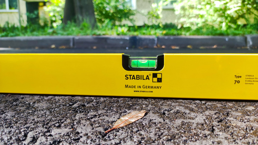 Крупный план пузырькового уровня STABILA на зернистом асфальтовом покрытии