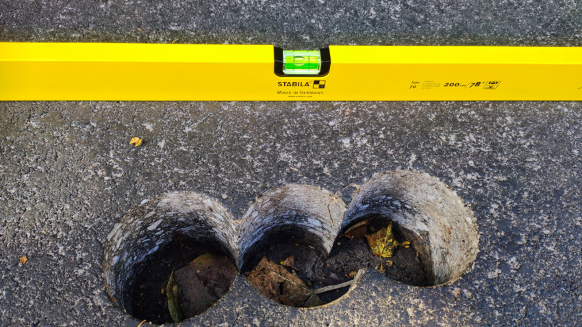 Отверстия после кернения в асфальте рядом со строительным уровнем STABILA
