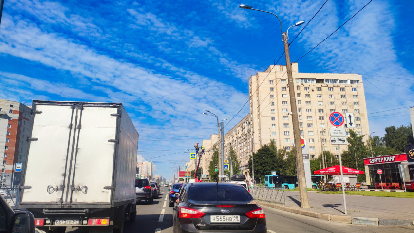 Городская улица с плотным движением, дорожными знаками и рабочей автовышкой
