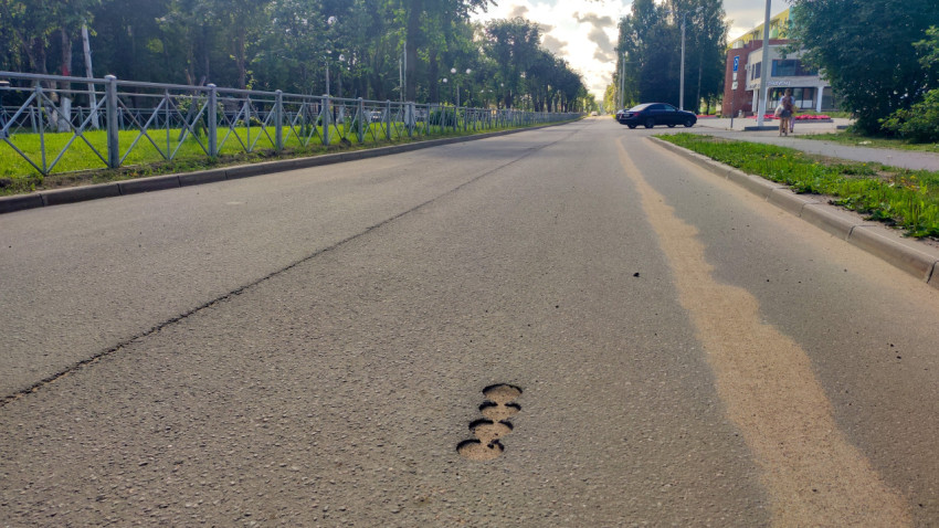Круглые отверстия от кернения в асфальте на проезжей части городской улицы