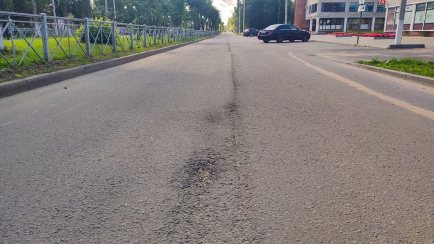 Неровный ремонтный шов и разрушение покрытия на асфальтовой дороге возле торгового здания