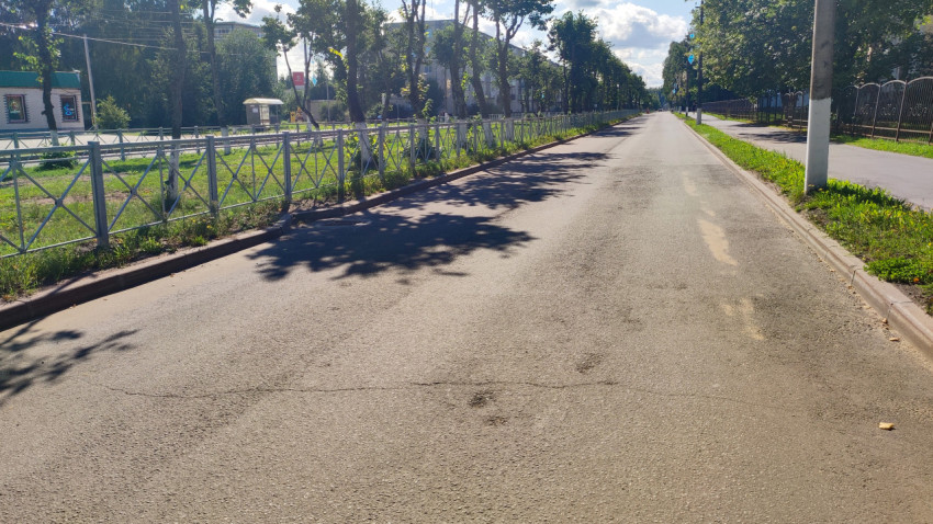 Пустая городская улица с остановкой, ограждениями и проводами над дорогой