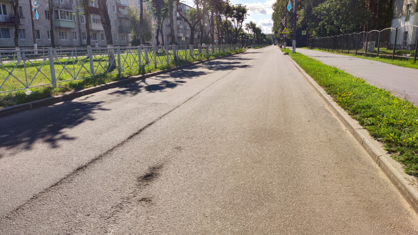 Асфальтовая дорога с бордюром и зелёной полосой у тротуара в жилом квартале