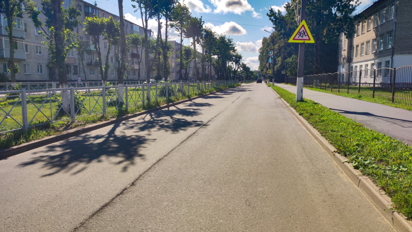 Предупреждающий дорожный знак «Дети» на улице рядом с тротуаром и ограждениями