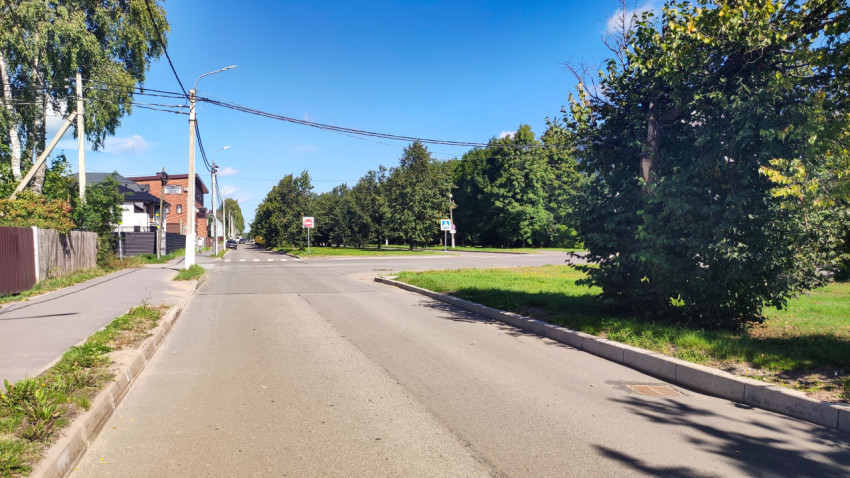 Перекрёсток с пешеходным переходом и дорожными знаками рядом с зелёной зоной