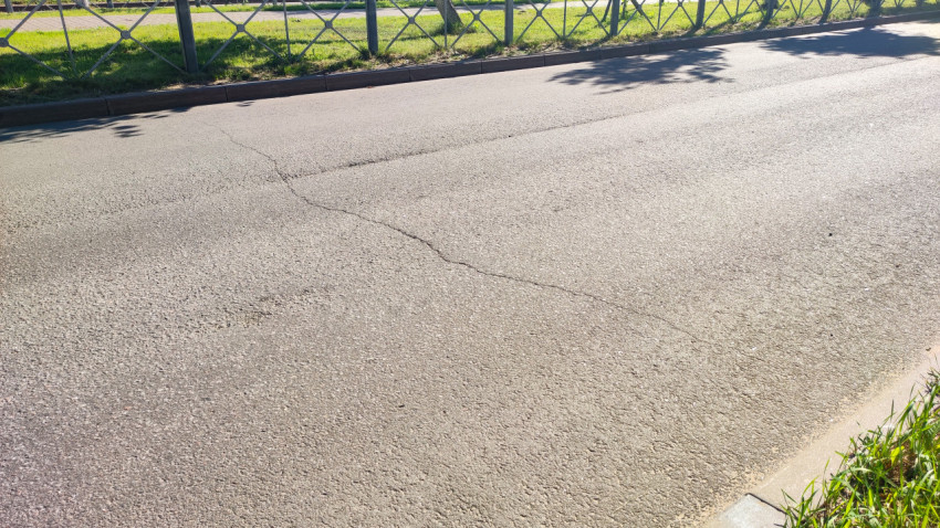 Крупный план серого асфальта с линией стыка и признаками износа дорожного покрытия