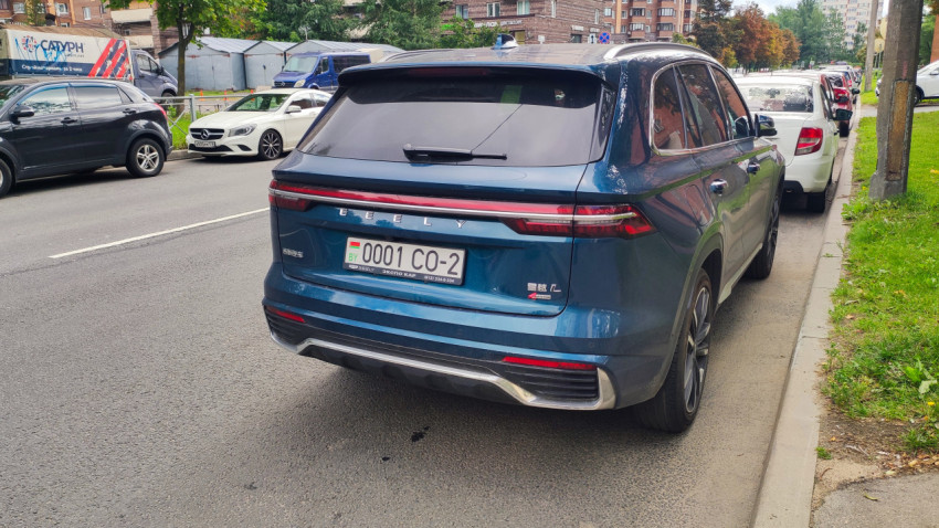 Припаркованный кроссовер Geely на обочине рядом с другими машинами в жилом районе