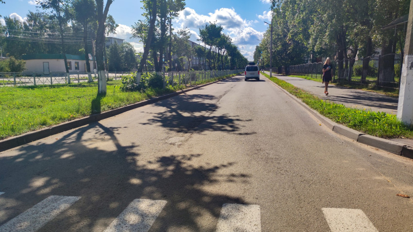 Прямая городская улица с пешеходным переходом, тротуаром и автомобилями в перспективе