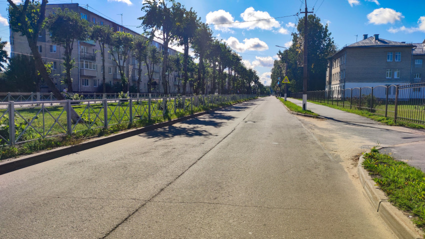 Городская улица с предупредительным знаком, аллеей деревьев и жилыми пятиэтажками