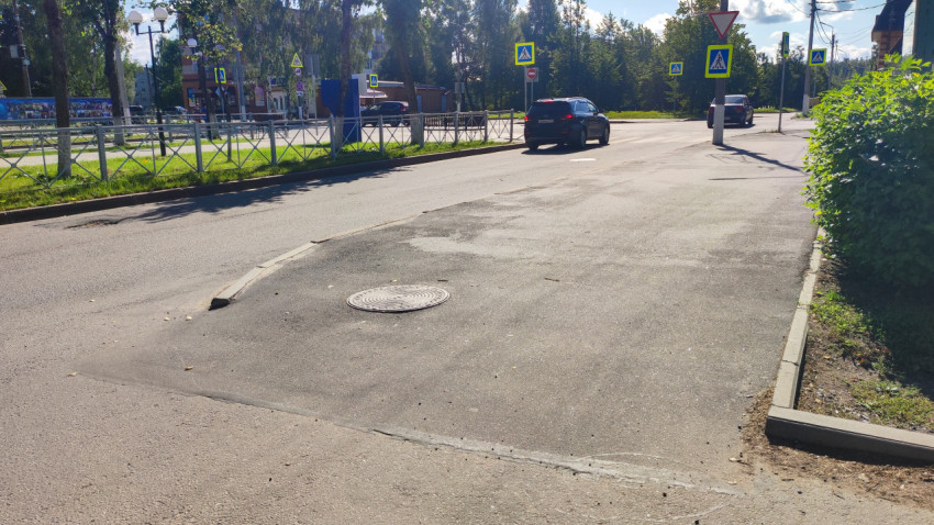 Участок дороги с асфальтовой заплаткой и люком на городском перекрёстке