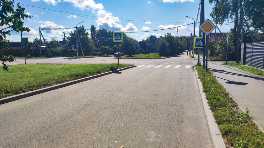 Пешеходный переход с предупреждающими дорожными знаками на прямом участке асфальтовой дороги